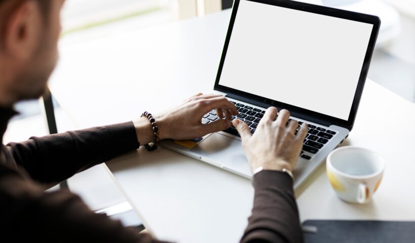 Freelancer worker using laptop, tipping, working on online project, sitting at workplace